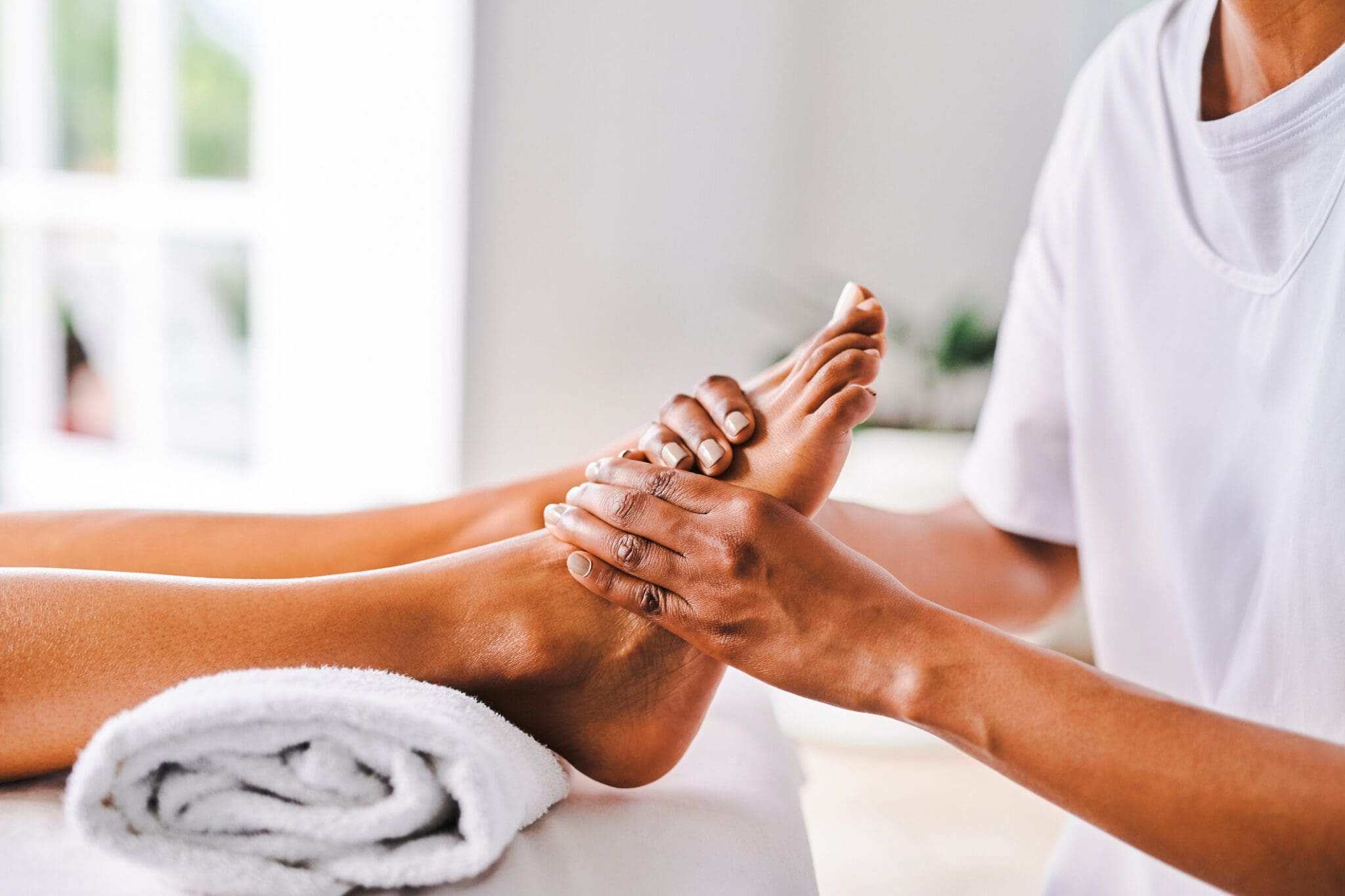 Foot massage therapy session on white towel.