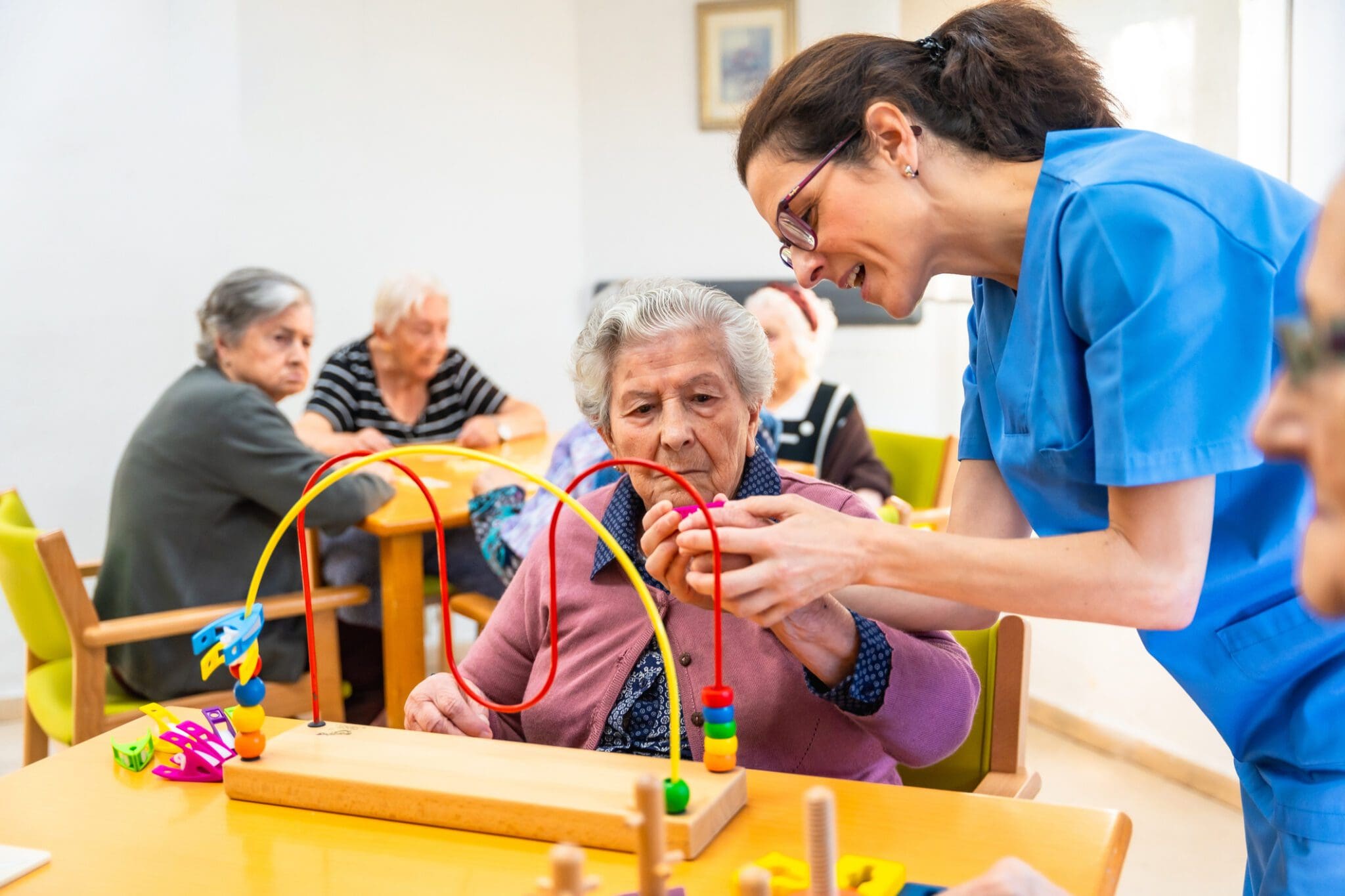Elderly woman assisted with activity toy.