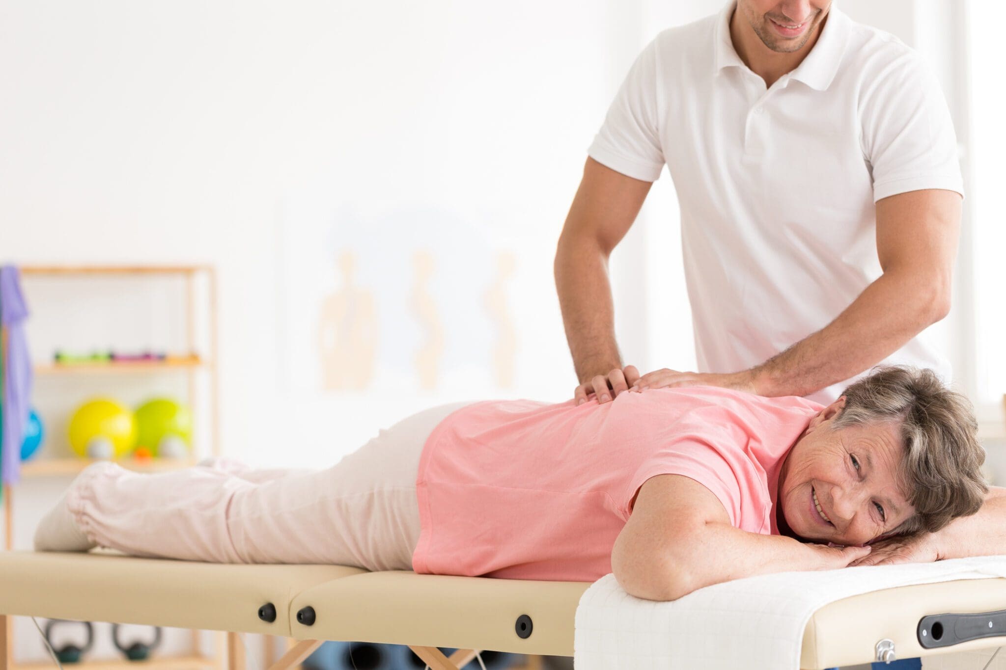 Elderly woman receiving a back massage therapy.